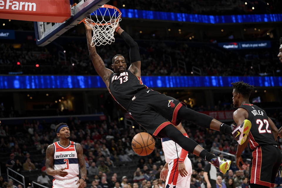 Miami Heat forward Bam Adebayo (13) swings from the rim after his dunk during the first half of an NBA basketball game as Washington Wizards guard Bradley Beal (3) looks on Sunday, March 8, 2020, in Washington. (AP Photo/Nick Wass)