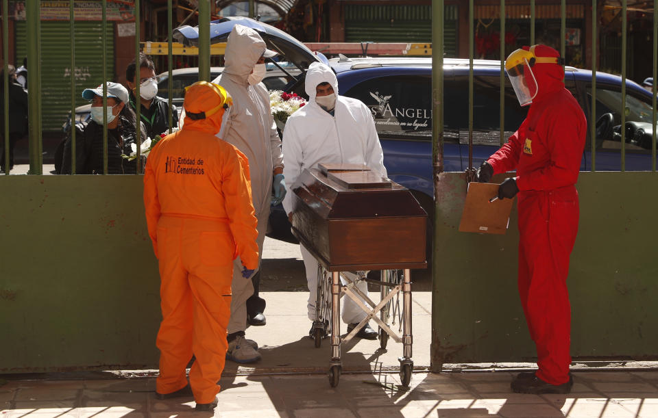 Trabajadores de una casa funeraria, con equipo para protegerse del coronavirus, empujan un ataúd al Cementerio General el lunes 18 de mayo de 2020, en La Paz, Bolivia. (AP Foto/Juan Karita)