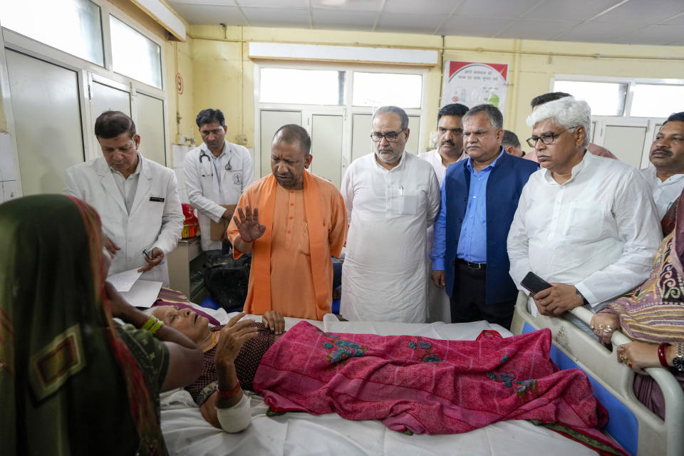 Uttar Pradesh State Chief Minister Yogi Adityanath, in saffron robes, gestures to a woman who was injured in a stampede as she receives treatment at Hathras district hospital, Uttar Pradesh, India, Wednesday, July 3, 2024. Thousands of people at a religious gathering rushed to leave a makeshift tent, setting off a stampede Tuesday that killed more than hundred people and injured scores. (AP Photo/Rajesh Kumar Singh)