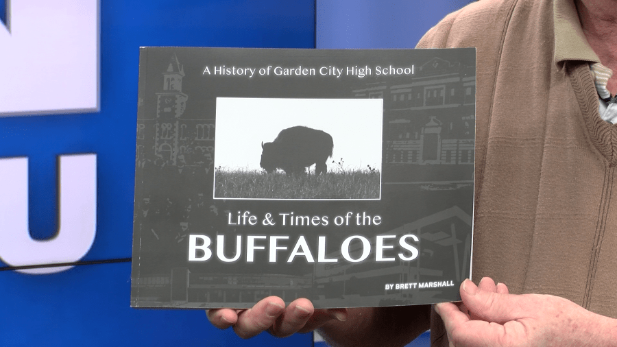 Brett Marshall holding his book, “Life & Times of the Buffaloes” – A History of Garden City High School in the KSN News studio on Feb. 23, 2024 (KSN Photo)