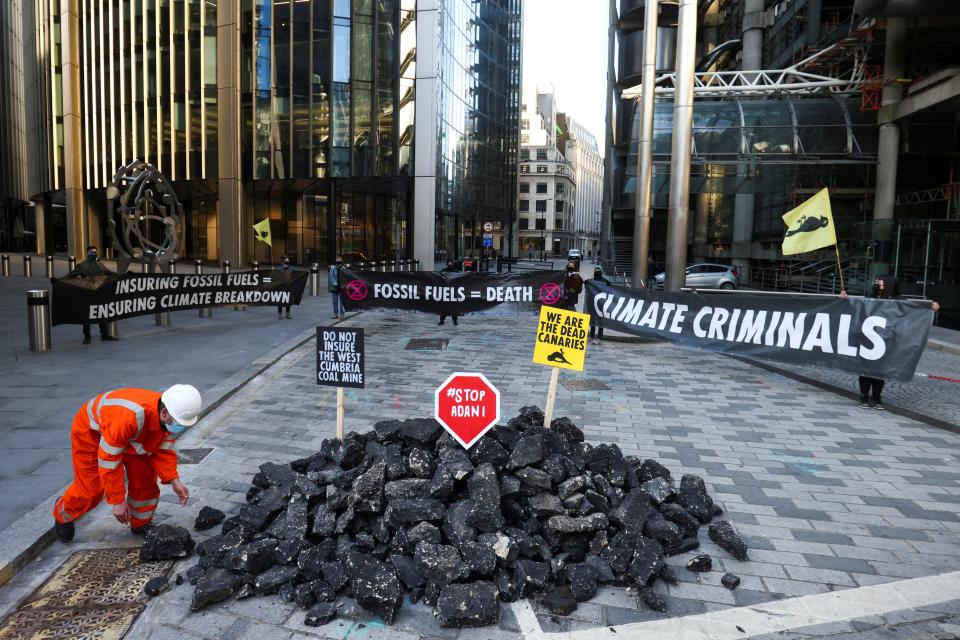 <p>Activists  hold banners as they stand next to fake coal</p> (REUTERS)