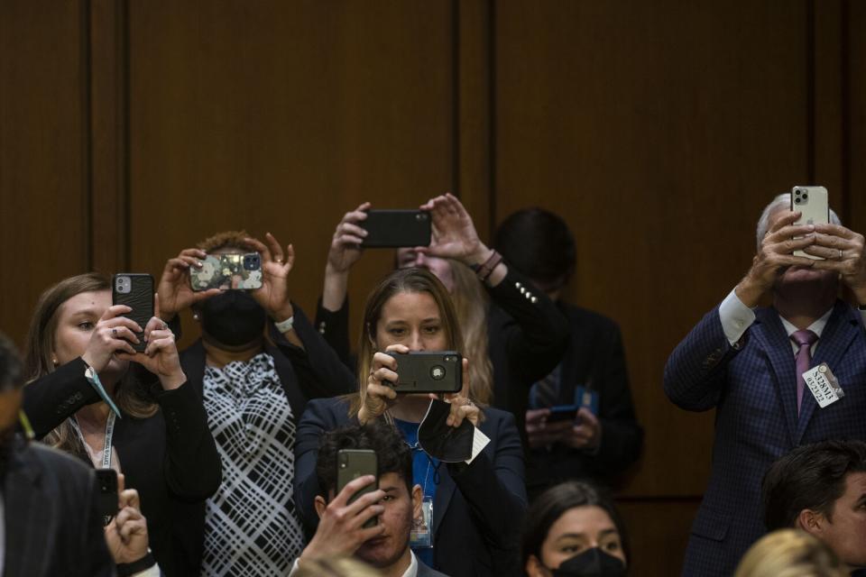 Visitors in the gallery raise their cellphone cameras.