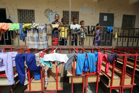 Children stand behind a fence at a school to which they have been evacuated from a village near Hodeidah airport amid fighting between government forces and Houthi fighters in Hodeidah, Yemen June 17, 2018. REUTERS/Abduljabbar Zeyad