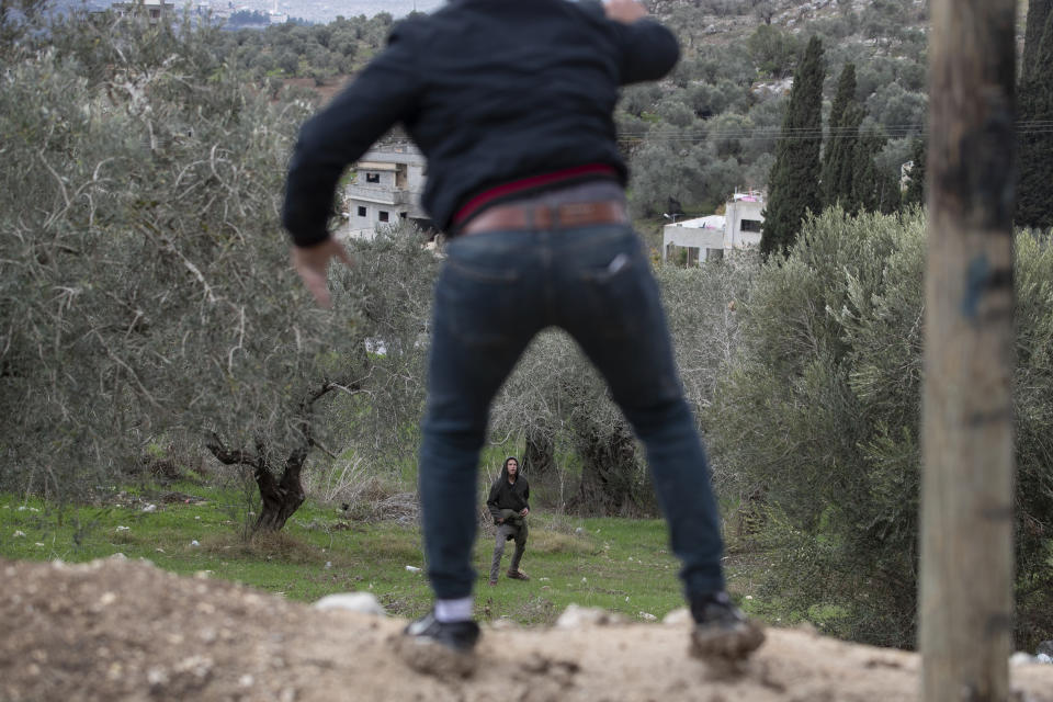 Jewish settlers, far back, clash with Palestinians, just after the funeral of Yehuda Dimentman, 25, who was killed in a shooting attack by a Palestinian gunman, in the West Bank village of Burqa, Friday, Dec. 17, 2021. Palestinian gunman opened fire Thursday night at a car filled with Jewish seminary students next to a West Bank settlement outpost, killing an Israeli man and lightly wounding two other people, Israeli officials said. (AP Photo/Majdi Mohammed)