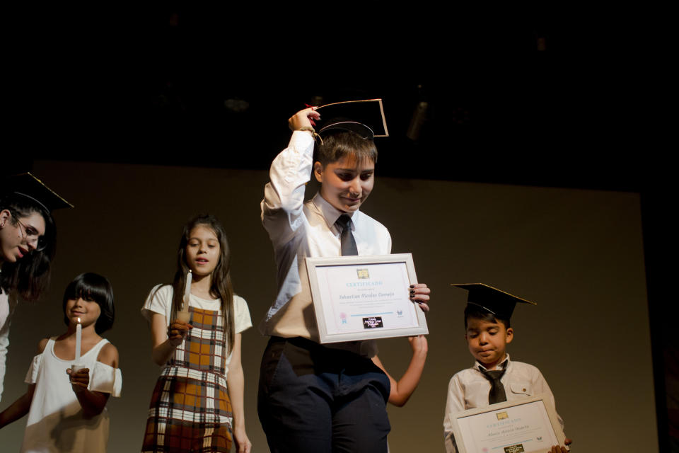 In this Dec.18, 2018 photo, transgender student Sebastian, center, carries his diploma after his graduation ceremony at the Amaranta Gomez school in Santiago, Chile. Classes began in April 2018 at a spaced loaned by a community center in the Chilean capital of Santiago. (AP Photo/Esteban Felix)