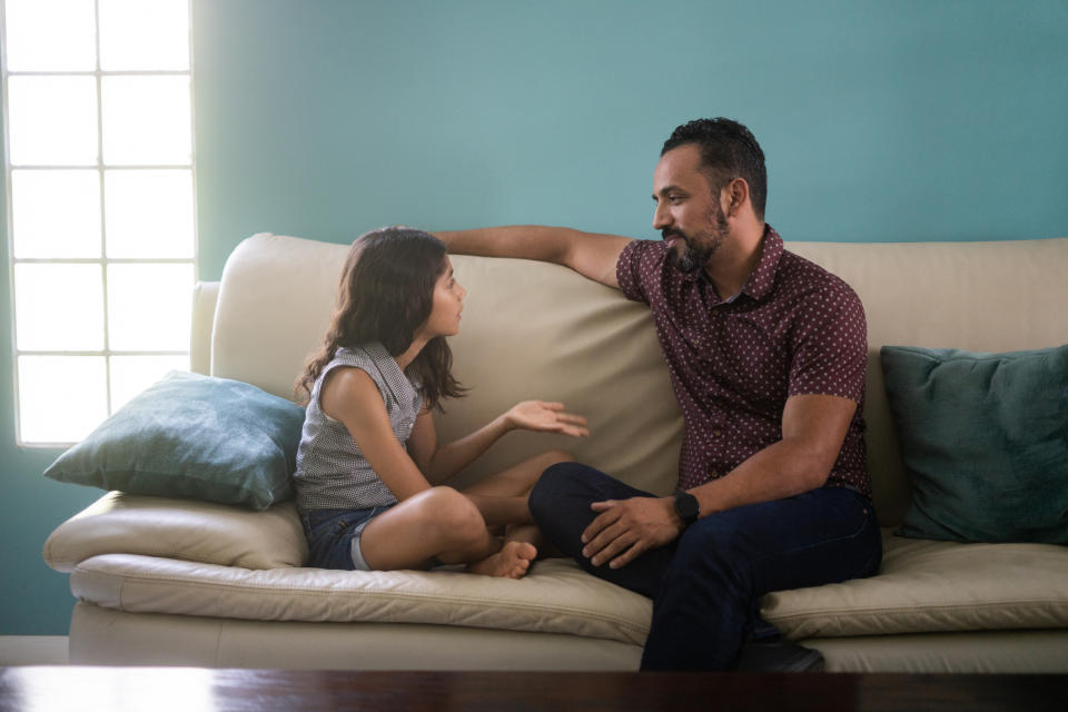 A parent and child have a serious conversation on a sofa