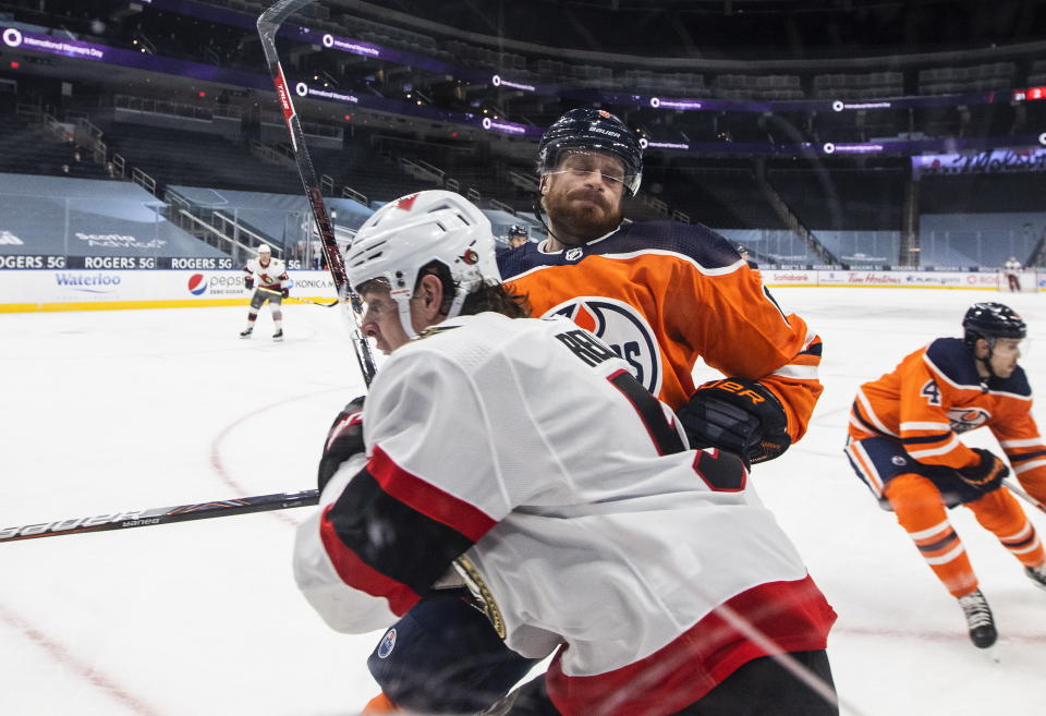 Edmonton Oilers' Adam Larsson (6) checks Ottawa Senators' Mike Reilly (5) during third-period NHL hockey game action in Edmonton, Alberta, Monday, March 8, 2021. (Jason Franson/The Canadian Press via AP)