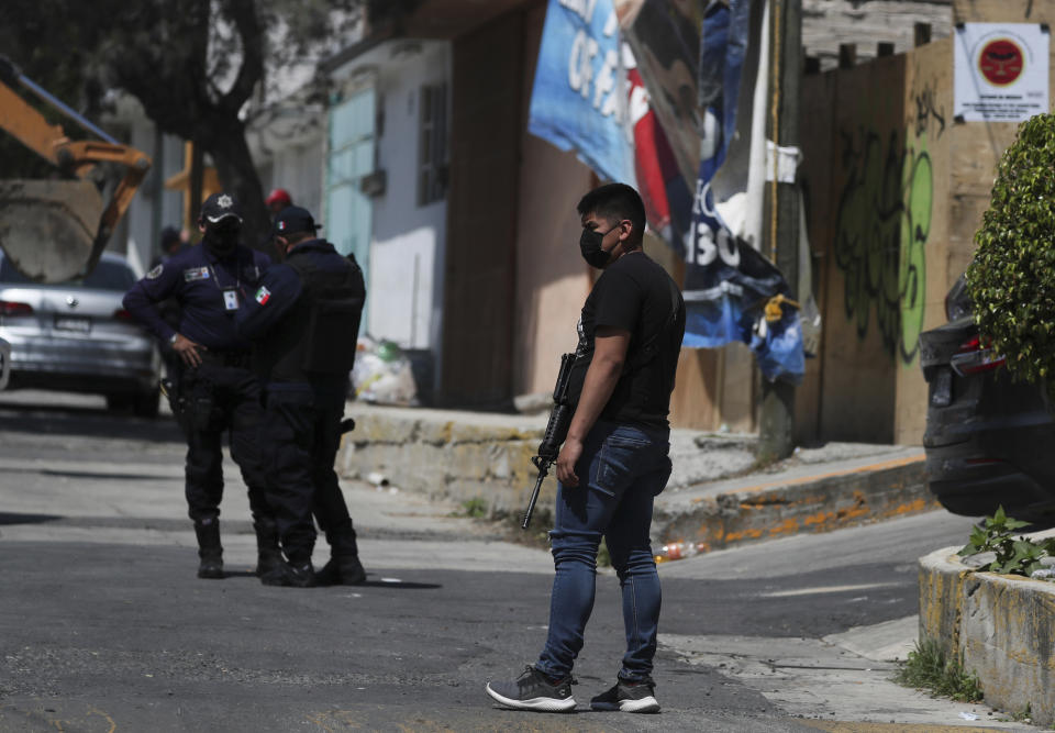 A police officer stands guard outside the house where they found bones under the floor in the Atizapan municipality of the State of Mexico, Thursday, May 20, 2021. Police have turned up bones and other evidence under the floor of the house where a man was arrested for allegedly stabbing a woman to death and hacking up her body. (AP Photo/Fernando Llano)