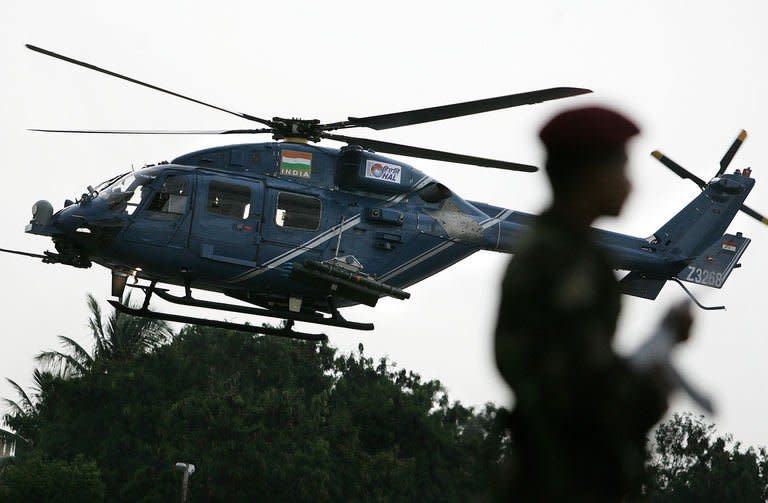 An Indian Army officer stands guard as the weaponised combat Dhruv Helicopter developed by Hindustan Aeronautics Limited (HAL) flies past in Bangalore on August 17, 2007. HAL has a near-monopoly in the country's aerospace industry