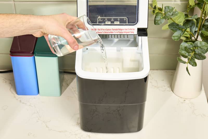 angled shot of water being poured into the empty ice maker.