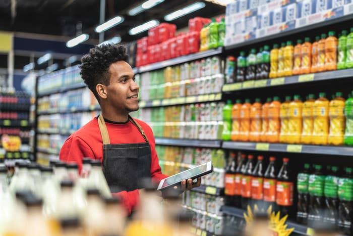 A grocery store employee checking inventory on a shelf