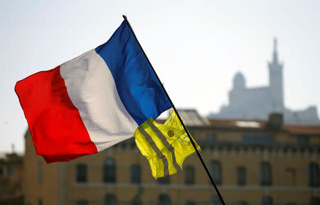 A French flag and a yellow vest flutter in the air as protesters take part in a demonstration of the "yellow vests" movement in Marseille, France, February 23, 2019. REUTERS/Jean-Paul Pelissier