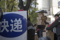 Delivery men distribute parcels on the streets of Beijing on Monday, Nov. 11, 2019. Chinese e-commerce giants Alibaba and JD.com reported a total of more than $50 billion in sales on Monday in the first half of Singles Day, an annual marketing event that is the world's busiest online shopping day. The sign reads "Delivery." (AP Photo/Ng Han Guan)