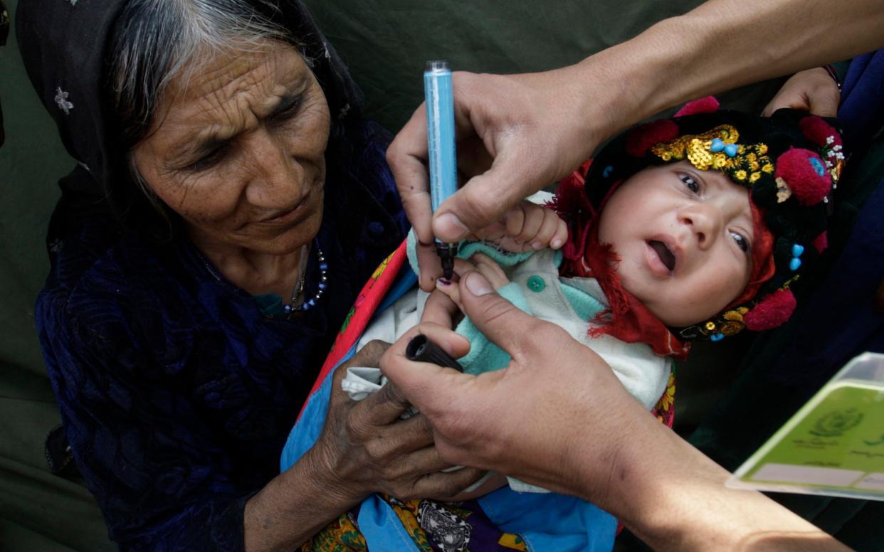 A Pakistani health worker marks an infant after immunisation with anti-polio drops in Lahore, Pakistan - AP