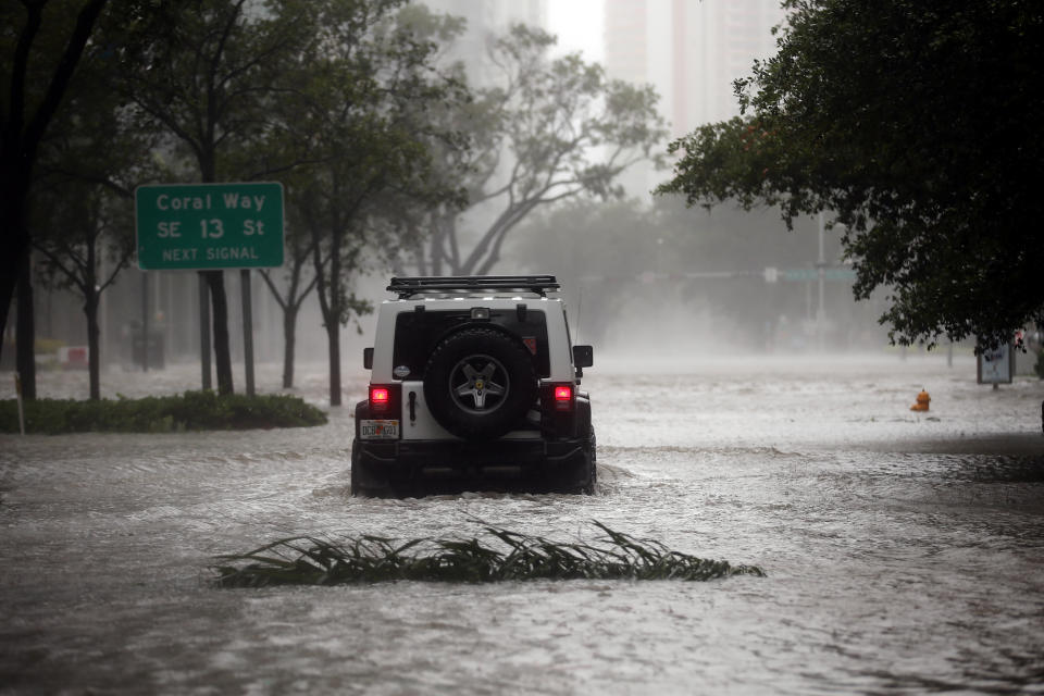 A vehicle drives along a flooded street in downtown Miami.