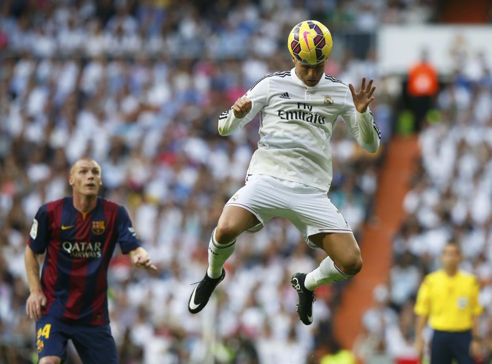 Real Madrid's Cristiano Ronaldo heads the ball as Barcelona's Jeremy Mathieu looks on during their Spanish first division "Clasico" soccer match at the Santiago Bernabeu stadium in Madrid October 25, 2014. REUTERS/Sergio Perez (SPAIN - Tags: SOCCER SPORT TPX IMAGES OF THE DAY)