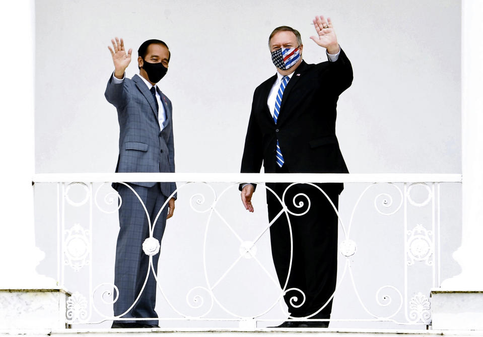 In this photo released by Indonesian Presidential Palace, Indonesian President Joko Widodo, left, and U.S. Secretary of State Mike Pompeo wave at photographers during their meeting at Bogor Presidential Palace in Bogor, West Java, Indonesia, Thursday, Oct. 29, 2020. Pompeo renewed the Trump administration's rhetorical onslaught against China in Indonesia on Thursday as the American presidential election looms. (Indonesian Presidential Palace via AP)