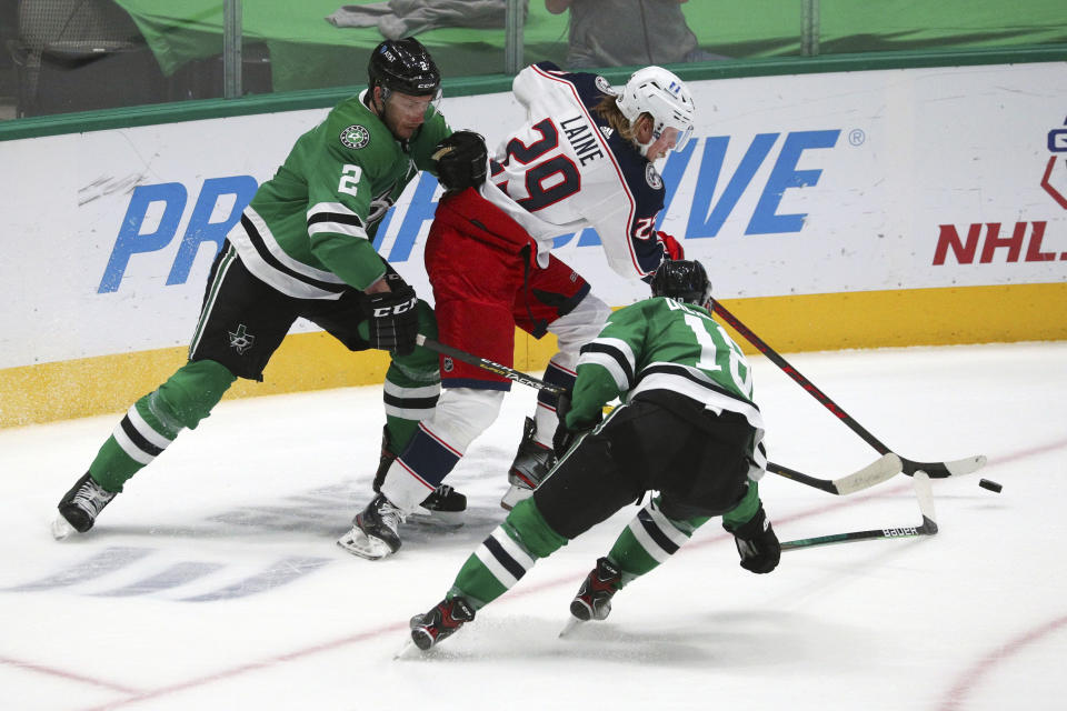 Dallas Stars defenseman Jamie Oleksiak (2) and center Jason Dickinson (18) try to get the puck away from Columbus Blue Jackets right wing Patrik Laine (29) during the first period of an NHL hockey game Thursday, April 15, 2021, in Dallas. (AP Photo/Richard W. Rodriguez)