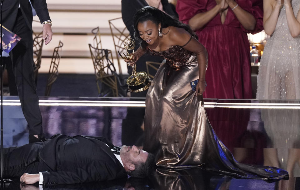 Quinta Brunson, right, winner of the Emmy for outstanding writing for a comedy series for "Abbott Elementary", checks on Jimmy Kimmel as he lays on stage at the 74th Primetime Emmy Awards on Monday, Sept. 12, 2022, at the Microsoft Theater in Los Angeles. (AP Photo/Mark Terrill)