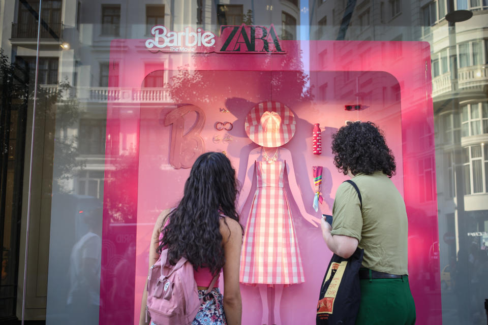 A girl and her mother look at the pink Barbie-themed fashion window display at a Zara store.