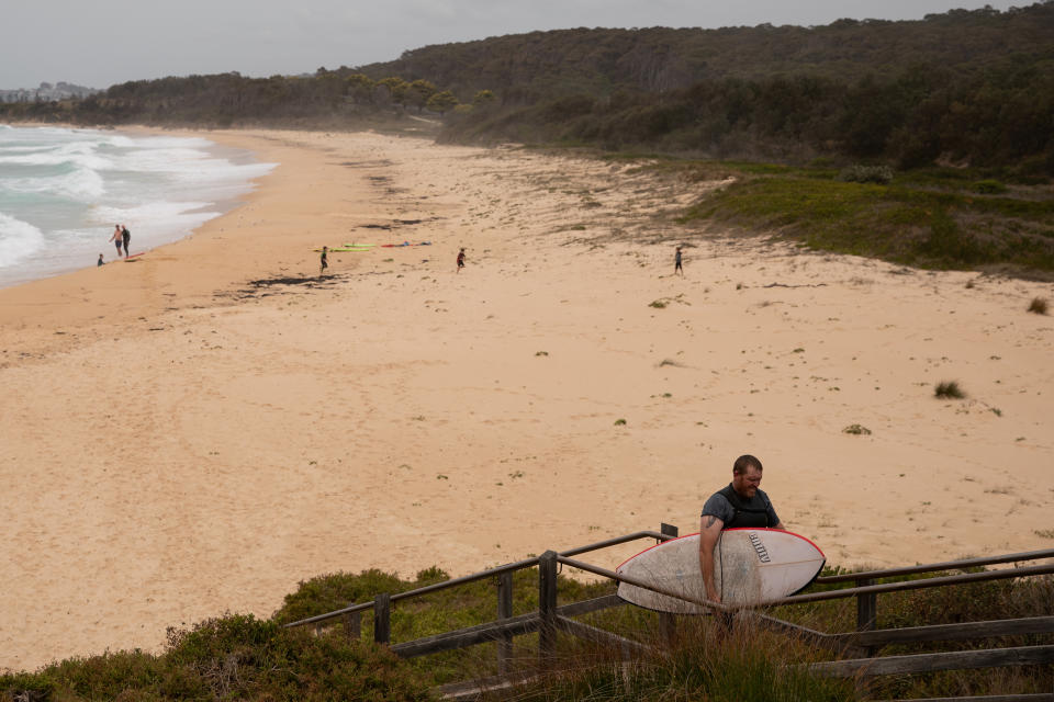 Peter Norman, 36, carries his surfboard as he leaves Duesbury beach, in Dalmeny