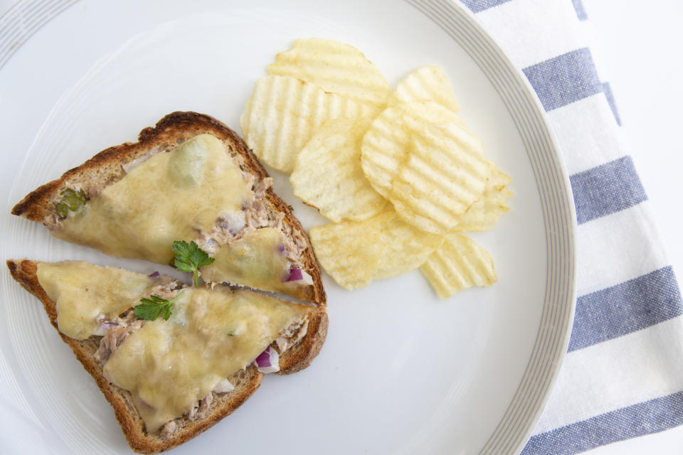 An open tuna melt and potato chips.