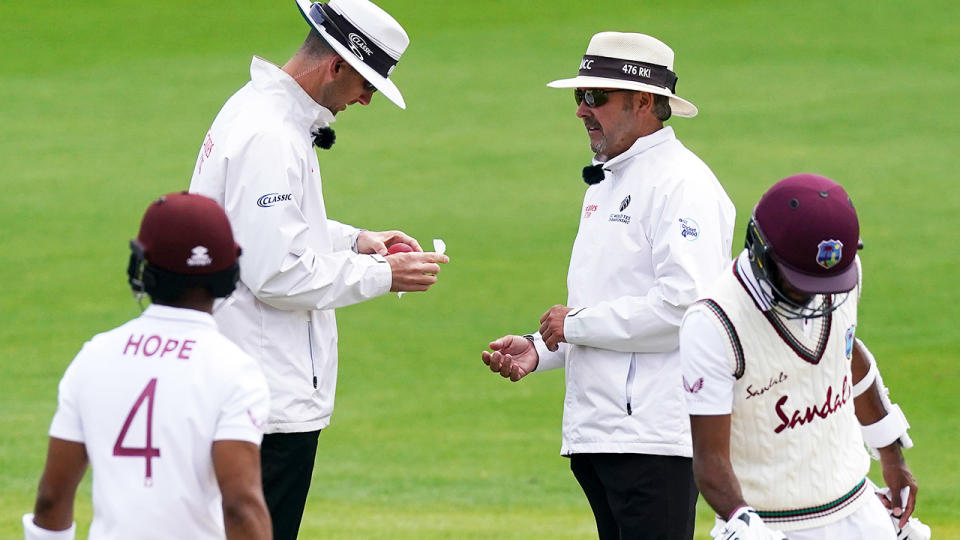 Umpires, pictured here disinfecting the ball during the second Test between England and West Indies.