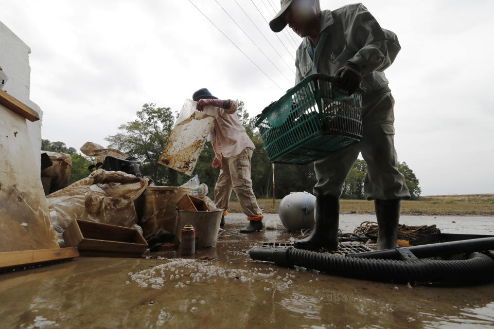 Residents Kazuo Saito, right, and Sumiko Saito clean up their home Monday, Oct. 14, 2019, in Kawagoe City, Japan. Typhoon Hagibis dropped record amounts of rain for a period in some spots, according to meteorological officials, causing more than 20 rivers to overflow. Some of the muddy waters in streets, fields and residential areas have subsided. But many places remained flooded, with homes and surrounding roads covered in mud and littered with broken wooden pieces and debris. (AP Photo/Eugene Hoshiko)