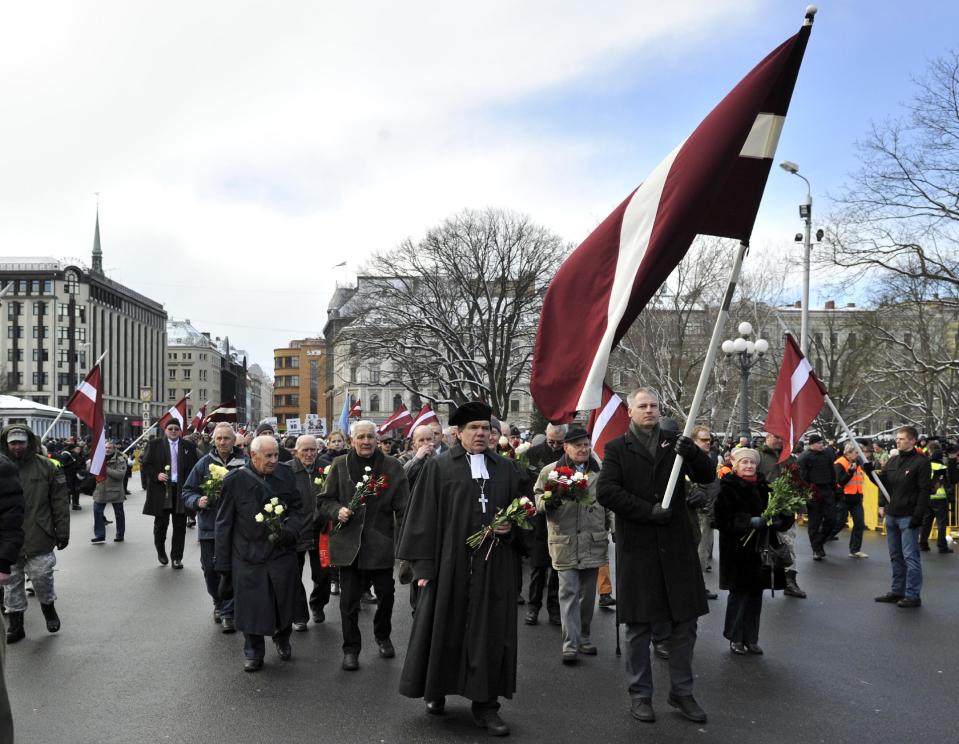 People carry Latvian flags as they march to the Freedom Monument to commemorate World War II veterans who fought in Waffen SS divisions, in Riga, Latvia, Sunday, March 16, 2014. People participate in annual commemorations of Latvian soldiers who fought in Nazi units during WWII. (AP Photo/Roman Kosarov, F64 Photo Agency)
