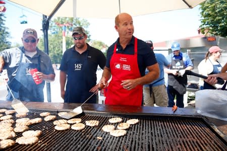 Democratic 2020 U.S. presidential candidate former U.S. Rep. John Delaney grills pork burgers at the Iowa Pork Producers tent at the Iowa State Fair in Des Moines