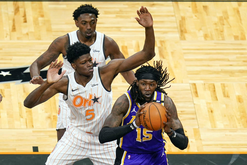 Los Angeles Lakers center Montrezl Harrell (15) passes the ball as his path to the basket is blocked by Orlando Magic center Mo Bamba (5) and forward Robert Franks, back left, during the first half of an NBA basketball game, Monday, April 26, 2021, in Orlando, Fla. (AP Photo/John Raoux)