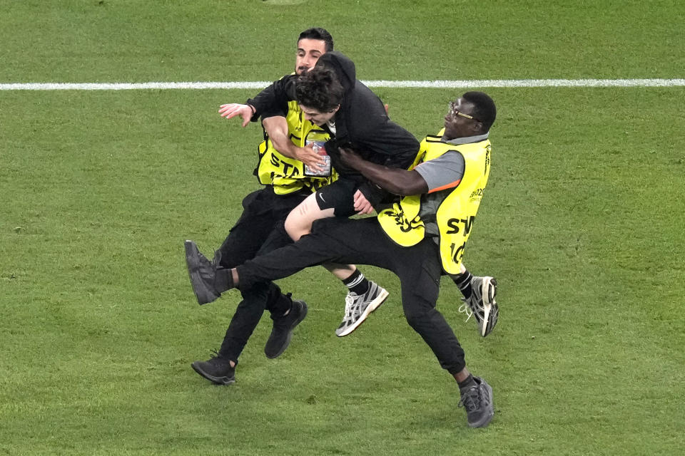 An invader is caught during a Group C match between the Denmark and Serbia at the Euro 2024 soccer tournament in Munich, Germany, Tuesday, June 25, 2024. Left is Denmark's goalkeeper Kasper Schmeichel. (AP Photo/Ariel Schalit)