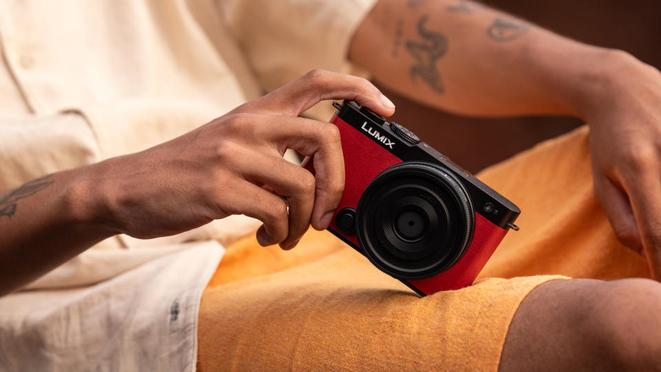 Panasonic Lumix S9 camera in red held in hand balanced on a person's leg