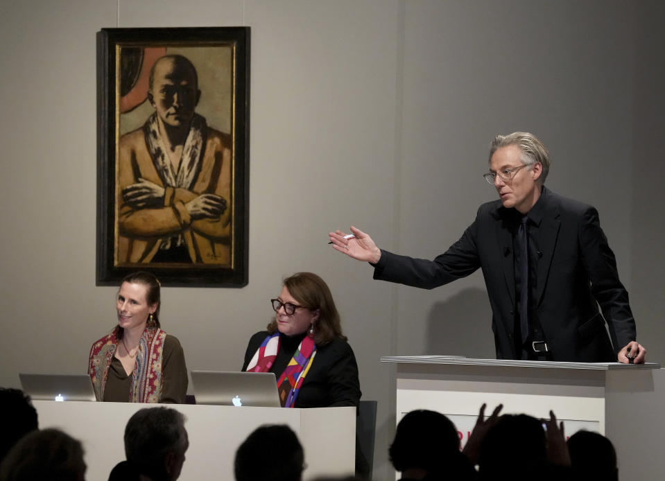 Auctioneer Markus Krause gestures in front of the painting 'Selbstbildnis gelb-rosa' (self-portrait yellow-rose), 1943 oil on canvas, by German painter Max Beckmann, as it is auctioned in Berlin, Germany, Thursday, Dec. 1, 2022. A self-portrait painted during World War II by German expressionist artist Max Beckmann has been sold in Berlin for 20 million euros ($20.7 million), which appears to be a record for an art auction in Germany. (AP Photo/Michael Sohn)