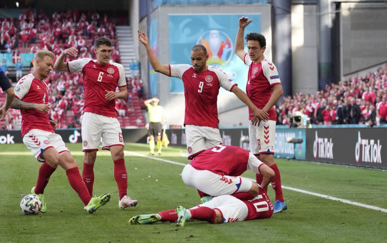 Jugadores de Dinamarca solicitan atención médica para su compañero Christian Eriksen, quien se desvaneció durante el partido de la Eurocopa ante Finlandia