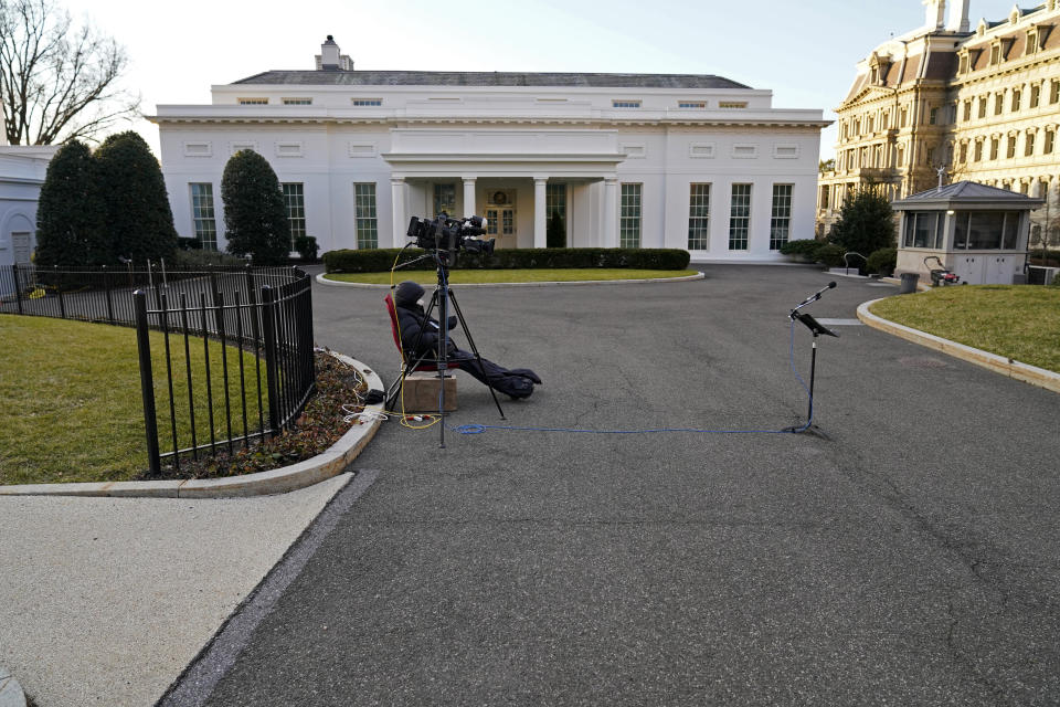 A cameraman waits by an unused microphone stand outside the West Wing at the White House, Tuesday, Jan. 19, 2021, in Washington. On President Donald Trump's last full day in office, there was an eerie quiet, with no public events scheduled, his last event being Jan. 12, seven days earlier. (AP Photo/Gerald Herbert)