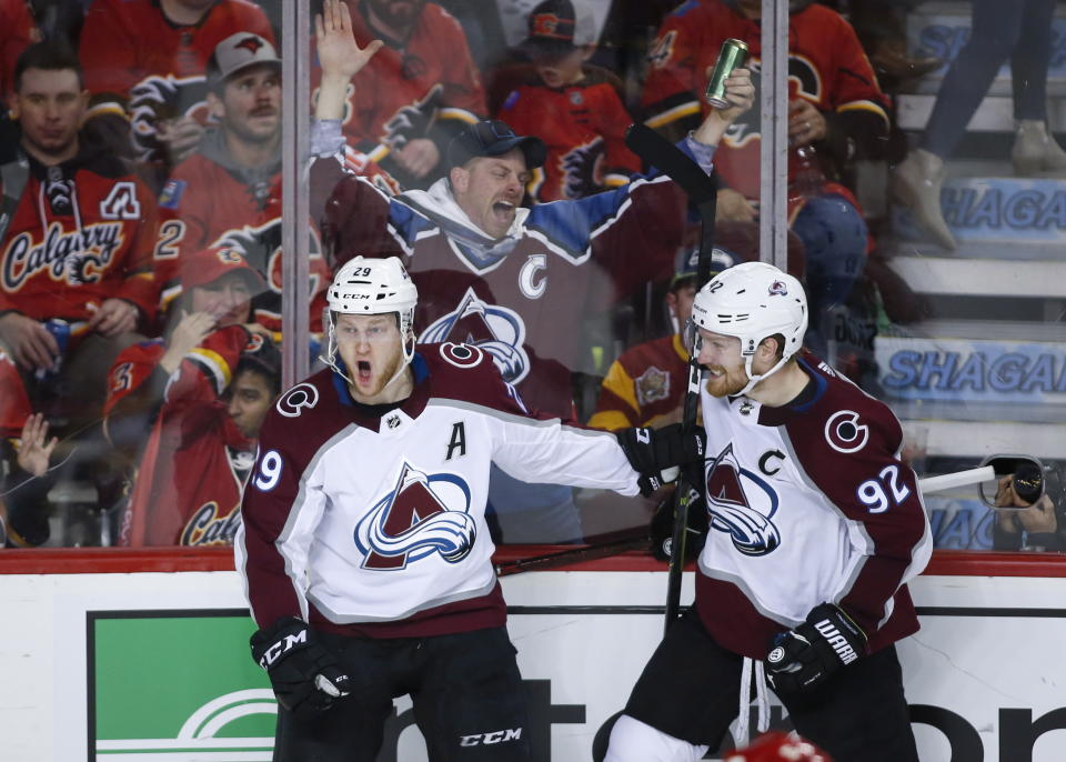 Colorado Avalanche center Nathan MacKinnon (29) celebrates his game-winning goal against the Calgary Flames with teammate Gabriel Landeskog (92) during overtime of an NHL hockey playoff game in Calgary, Alberta, Saturday, April 13, 2019. (Jeff McIntosh/The Canadian Press via AP)