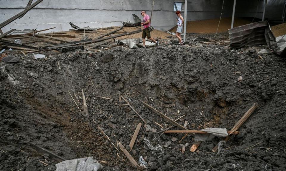People walk past a crater left by a Russian missile strike inside a wheat grain storage facility in Zaporizhzhia last week.
