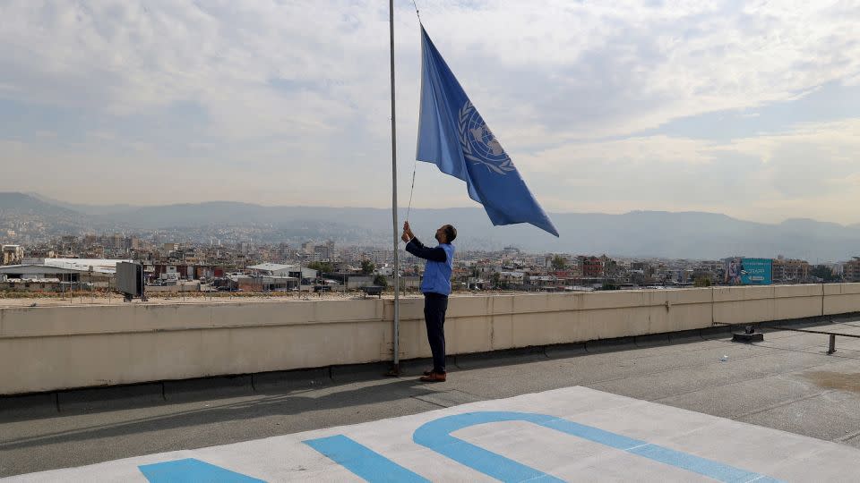 An employee at the United Nations Relief and Works Agency (UNRWA) lowers the UN flag on the roof of the organization's regional offices in the Lebanese capital Beirut on November 13, 2023. - Anwar Amro/AFP/Getty Images