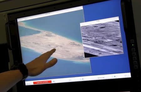 A U.S. Navy crewman aboard a P-8A Poseidon surveillance aircraft points to a computer screen purportedly showing Chinese construction on the reclaimed land of Fiery Cross Reef in the disputed Spratly Islands in this still image from video provided by the United States Navy May 21, 2015. REUTERS/U.S. Navy/Handout via Reuters ATTENTION EDITORS - THIS PICTURE WAS PROVIDED BY A THIRD PARTY. REUTERS IS UNABLE TO INDEPENDENTLY VERIFY THE AUTHENTICITY, CONTENT, LOCATION OR DATE OF THIS IMAGE. THIS PICTURE WAS PROCESSED BY REUTERS TO ENHANCE QUALITY. EDITORIAL USE ONLY. NOT FOR SALE FOR MARKETING OR ADVERTISING CAMPAIGNS.