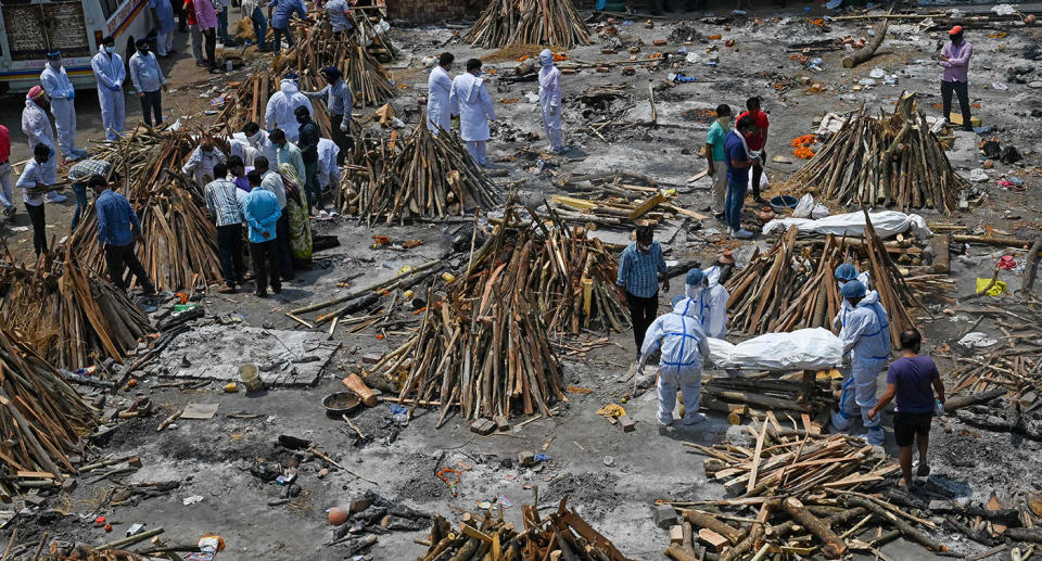 TOPSHOT - Family members and relatives prepare the funeral pyre of victims who died of the Covid-19 coronavirus during mass cremation held at a crematorium in New Delhi on April 27, 2021. (Photo by Prakash SINGH / AFP) (Photo by PRAKASH SINGH/AFP via Getty Images)