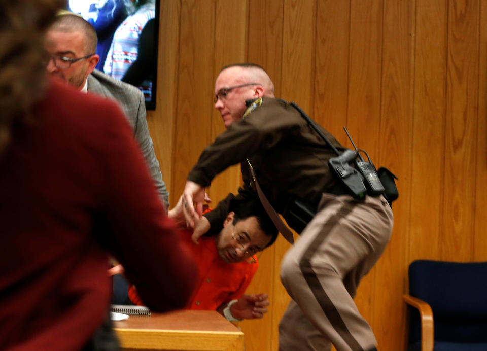 Nassar's attorney and a law enforcement officer deflect Margraves' attack. (Photo: Rebecca Cook/Reuters)