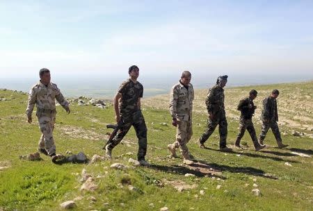 Members of the Kurdish Peshmerga forces walk near their security point on Bashiqa mountain, overlooking Islamic State held territories of Mosul, 12 km northeast of Mosul City March 7, 2015. REUTERS/Asmaa Waguih