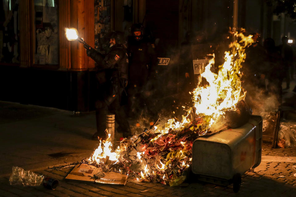 A police officer shoots rubber bullets at protesters during clashes following a protest condemning the arrest of rap singer Pablo Hasel in Madrid, Spain, Wednesday, Feb. 17, 2021. Police fired rubber bullets and baton-charged protesters as clashes erupted for a second night in a row Wednesday at demonstrations over the arrest of Spanish rap artist Pablo Hasel. Many protesters threw objects at police and used rubbish containers and overturned motorbikes to block streets in both Madrid and Barcelona. (AP Photo/Manu Fernandez)