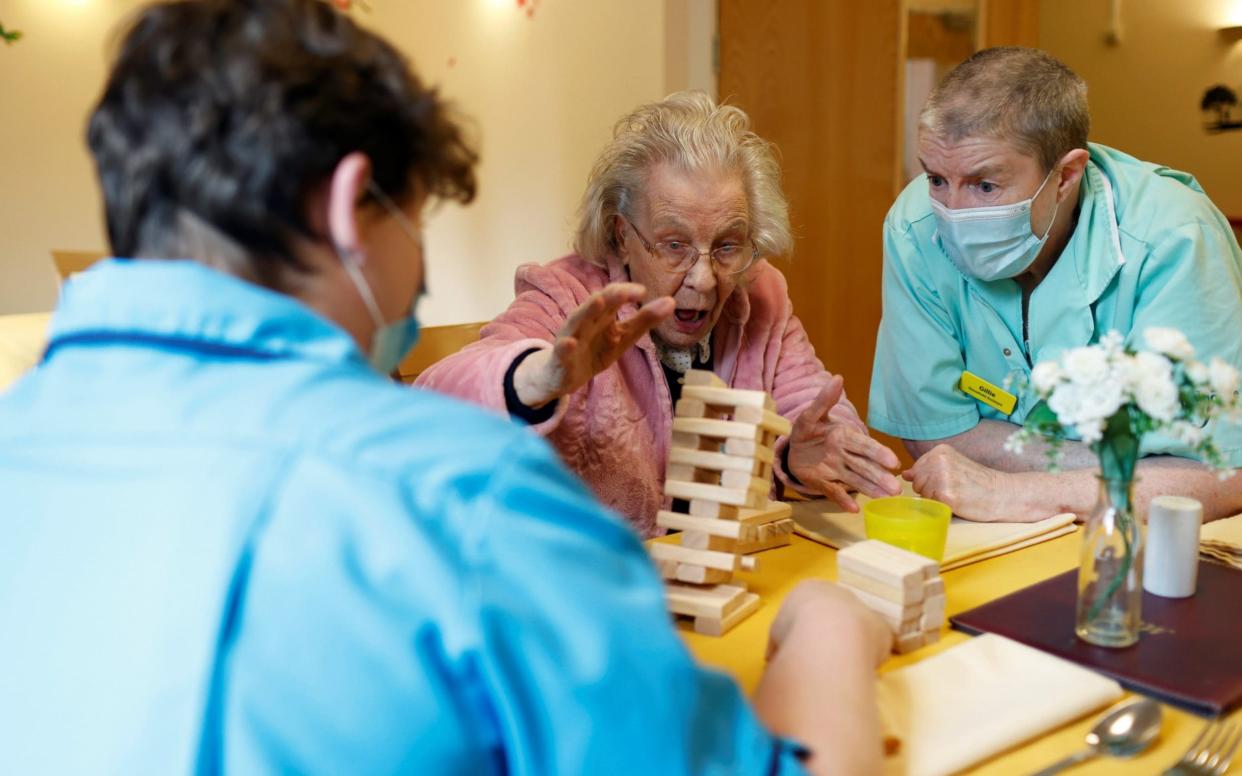 Senior carer Jo Battams and housekeeper Gillie Gillroy, who remain on site with six colleagues, play Jenga with resident Iris Hook at Fremantle Trust care home, amid the outbreak of the coronavirus disease - Reuters