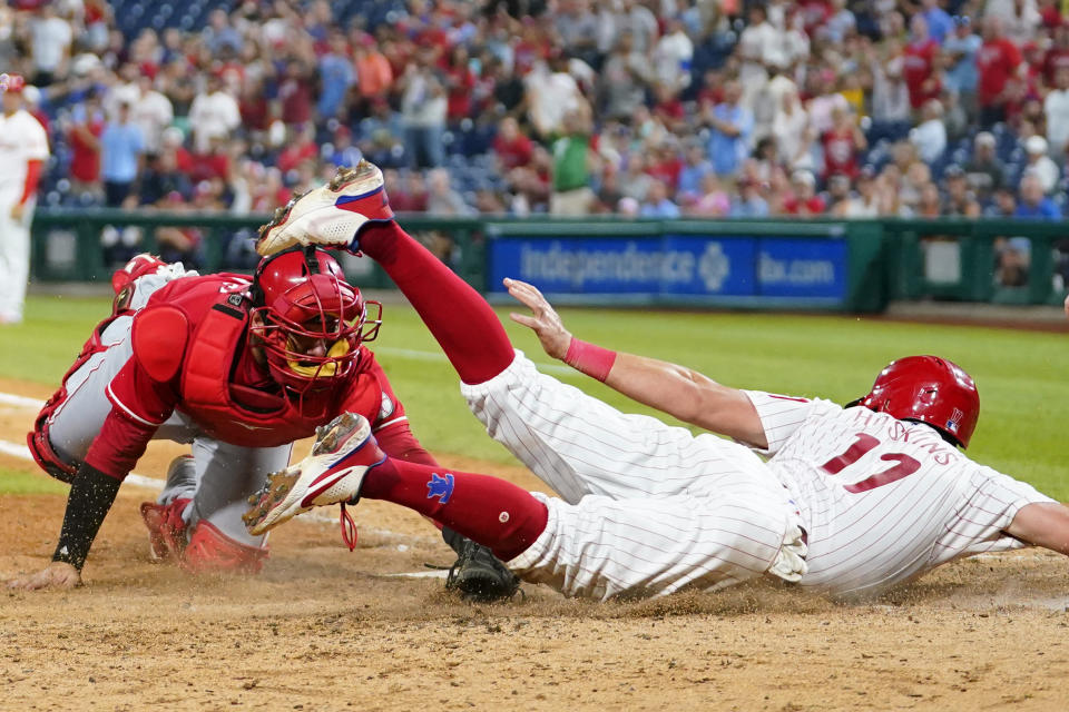 Philadelphia Phillies' Rhys Hoskins, right, is tagged out at home by Cincinnati Reds catcher Austin Romine after trying to score on a double by J.T. Realmuto during the seventh inning of a baseball game, Wednesday, Aug. 24, 2022, in Philadelphia. (AP Photo/Matt Slocum)