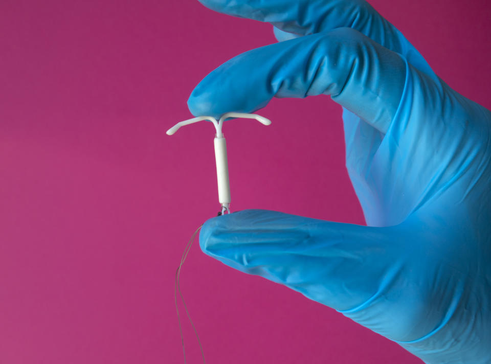 A health-care professional holds an IUD in their latex glove-covered hand. (Photo via Getty Images)