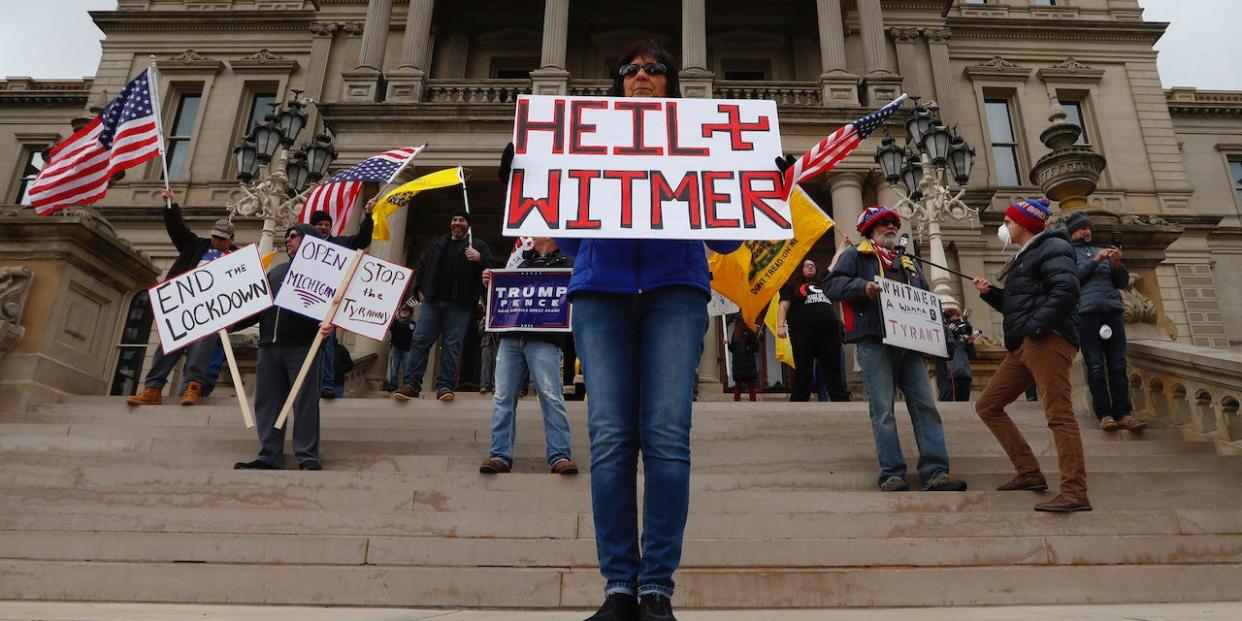 Dawn Perreca protests on the front steps of the Michigan State Capitol building in Lansing, Mich., Wednesday, April 15, 2020.