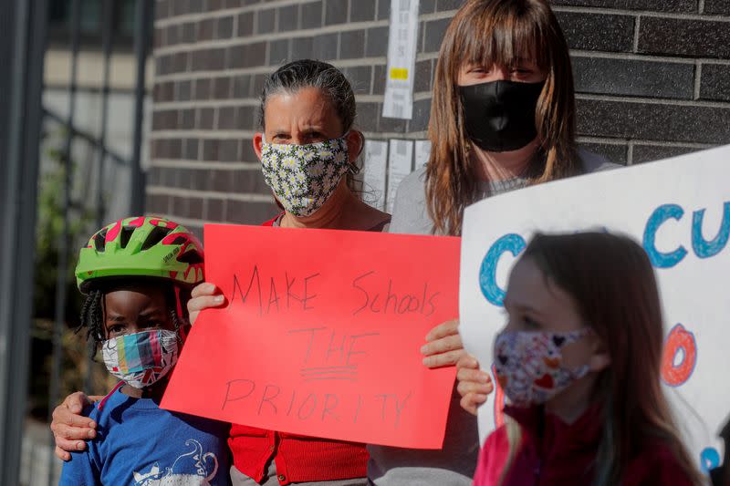 Parents and children hold signs during a protest against the closing of Public School 130 outside the school building for safety reasons, following the outbreak of the coronavirus disease (COVID-19) in Brooklyn, New York