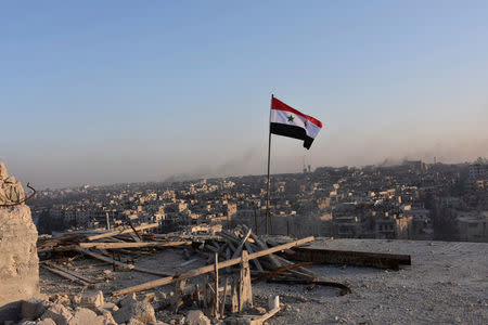 A Syrian national flag flutters near a general view of eastern Aleppo after Syrian government soldiers took control of al-Sakhour neigbourhood in Aleppo, Syria in this handout picture provided by SANA on November 28, 2016. SANA/Handout via REUTERS